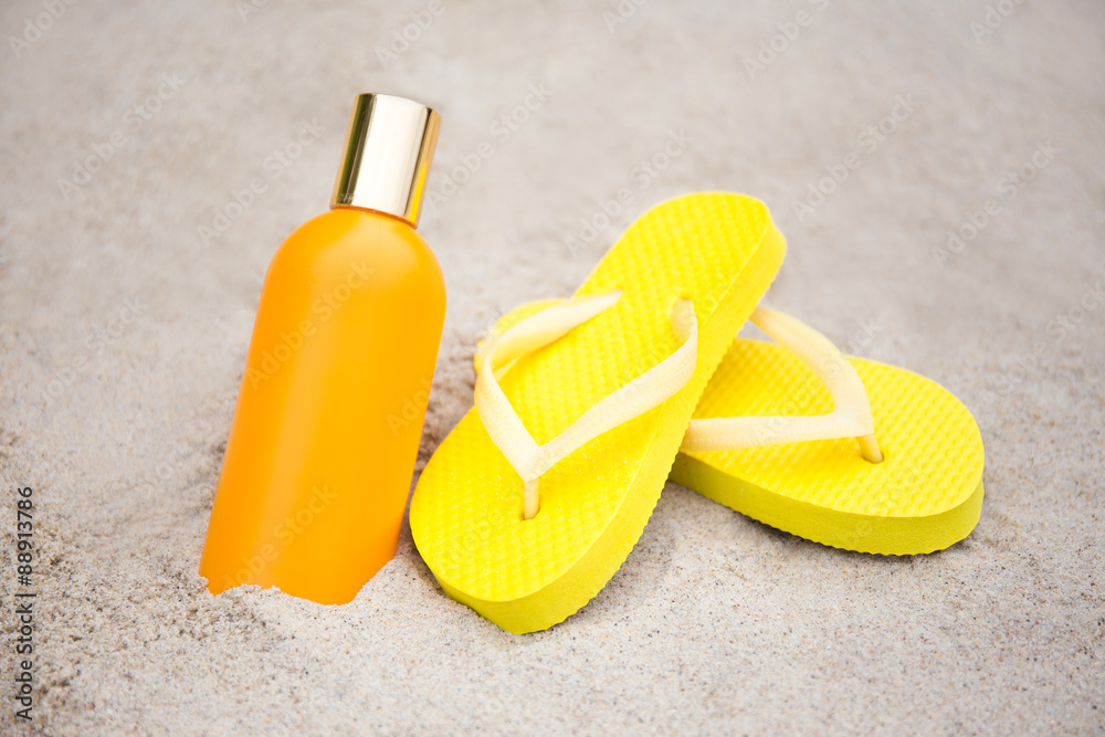 summer and skin care concept - slippers and suntan lotion bottle summer and skin care concept - slippers and suntan lotion bottle