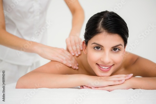 Pretty brunette enjoying a massage smiling at camera