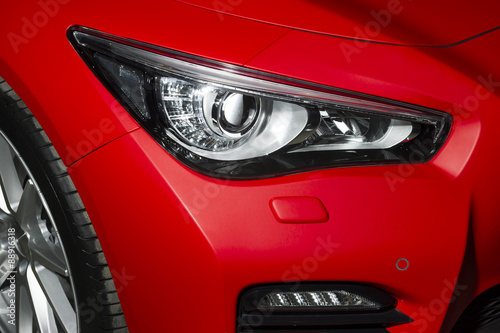 Predatory car headlight and hood of powerful sports car with matte red paint and wheel with silver disc  © antonmatveev
