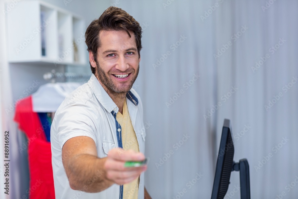 Smiling cashier handing back credit card Smiling cashier handing back credit card