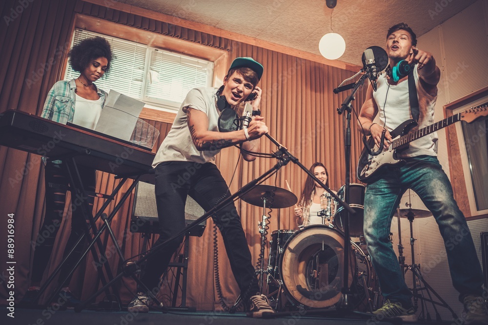 Multiracial music band performing in a recording studio - obrazy, fototapety, plakaty 