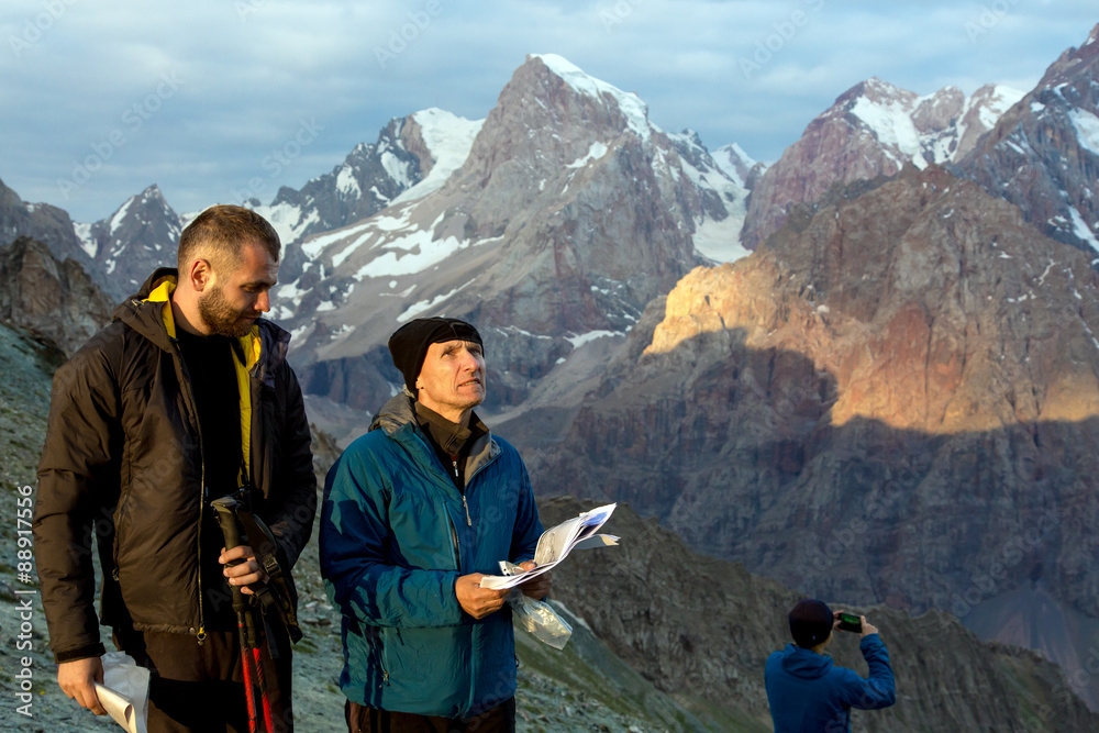 People travelling in mountain landscape.
Two mature men looking up holding climbing guidebooks and thinking about future difficult climbing ascent