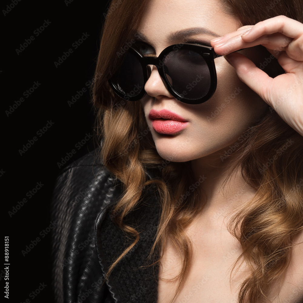 Beautiful girl in dark sunglasses, with curls and evening makeup. Beauty face. Picture taken in the studio on a black background. Beautiful girl in dark sunglasses, with curls and evening makeup. Beauty face. Picture taken in the studio on a black background.