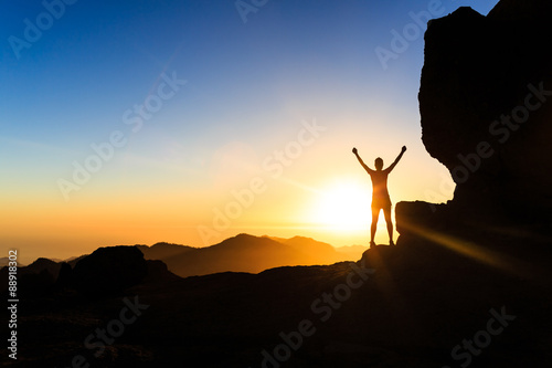 Woman climber success silhouette in mountains  ocean and sunset