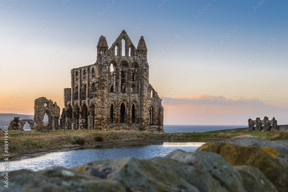 Naklejka premium Stone ruins of Whitby Abbey on the cliffs of Whitby, North Yorkshire, England at sunset.