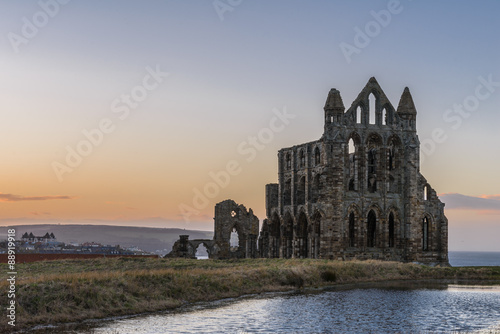 Stone ruins of Whitby Abbey on the cliffs of Whitby, North Yorkshire, England at sunset.