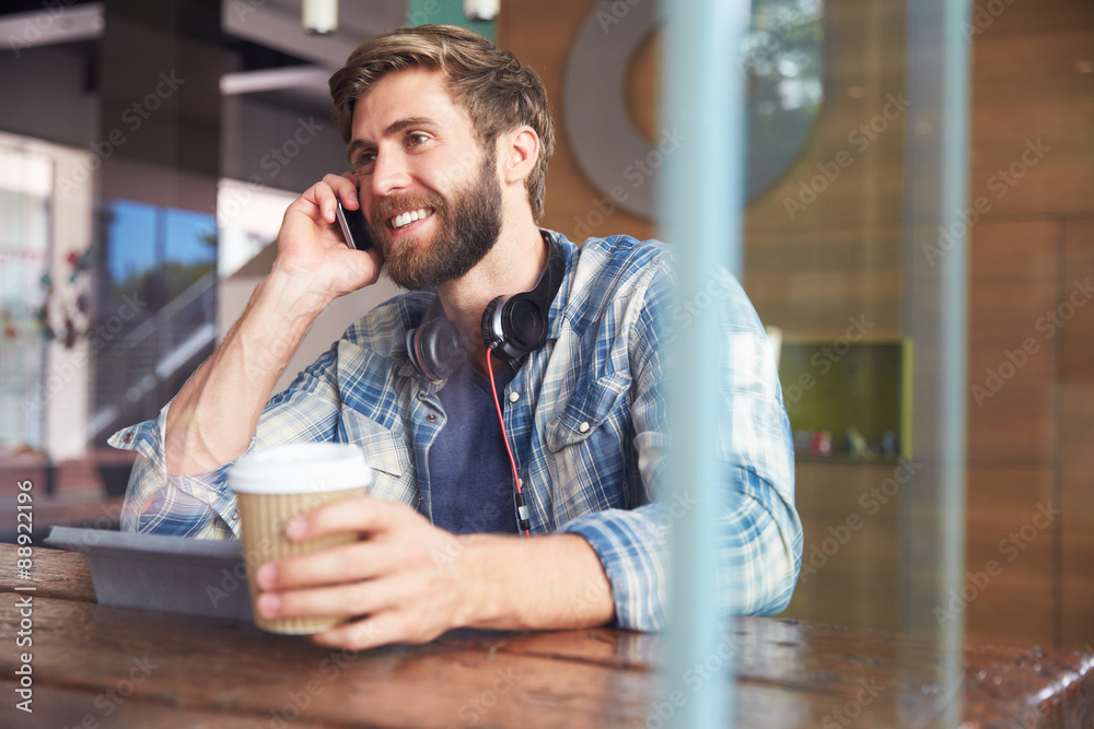 Businessman On Phone Using Digital Tablet In Coffee Shop