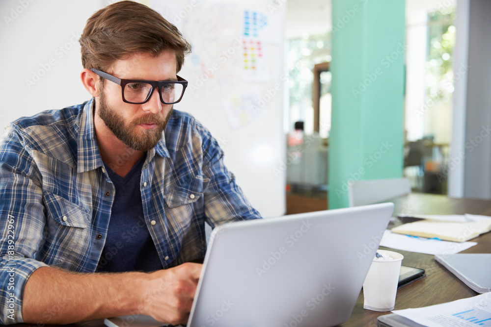 Businessman Sitting At Desk In Office Working On Laptop Businessman Sitting At Desk In Office Working On Laptop