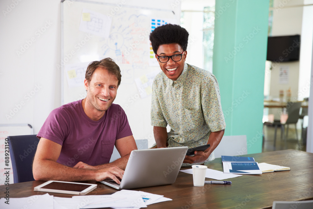 Two Businessmen Working On Laptop In Office Together