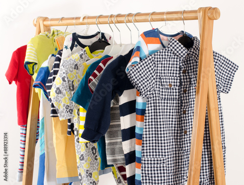 Dressing closet with clothes arranged on hangers.Colorful wardrobe of newborn,kids, toddlers, babies full of all clothes.Many t-shirts,pants, shirts,blouses, onesie hanging © iulianvalentin