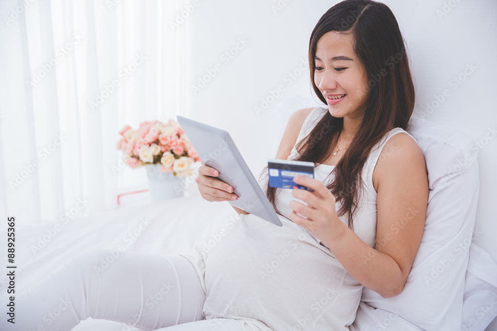 Beautiful pregnant asian woman holding tablet pc and credit card Beautiful pregnant asian woman holding tablet pc and credit card