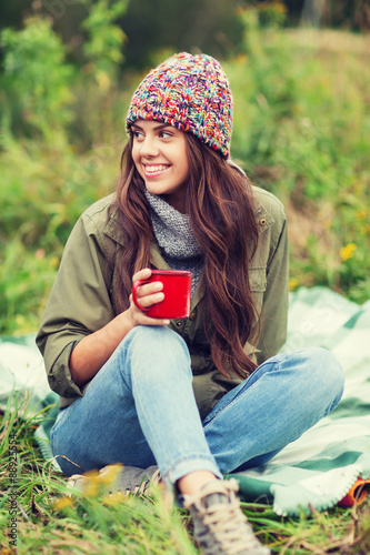 smiling young woman with cup sitting in camping photo