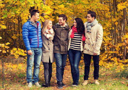 group of smiling men and women in autumn park