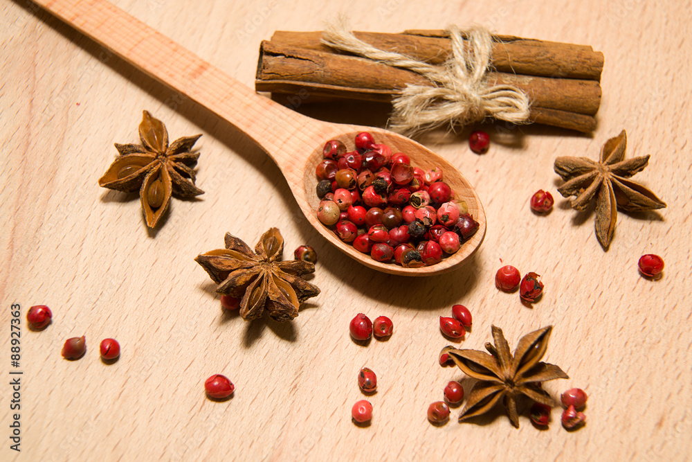 Spoon, grains of pepper, cinnamon and star anise on a wooden sur Spoon, grains of pepper, cinnamon and star anise on a wooden sur