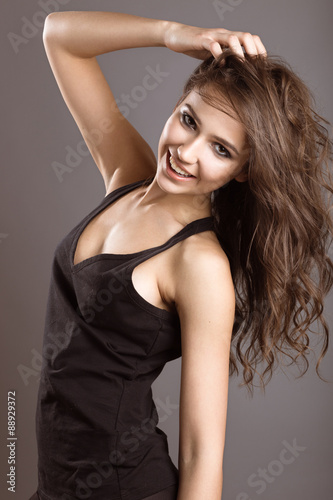 Beautiful young girl in sports style with loose hair. Picture taken in the studio on a brown background