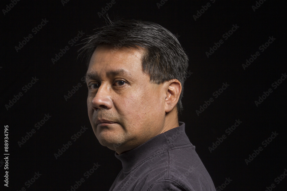 Fototapeta premium Studio portrait of a serious Hispanic male, over the shoulder