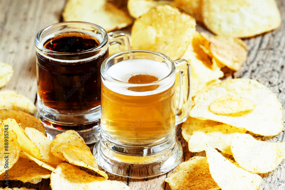 Dark and light beer and chips on the old wooden background, sele Dark and light beer and chips on the old wooden background, sele