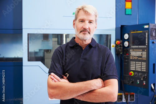 Portrait Of Male Engineer Operating CNC Machinery In Factory