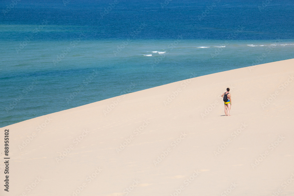 Girl walking on the white dunes on the beach of the Bazaruto Islands near Vilanculos in Mozambique with the Indian ocean in the background
