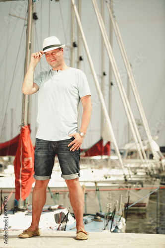 Handsome fashion man on pier in port with yachts. © Voyagerix