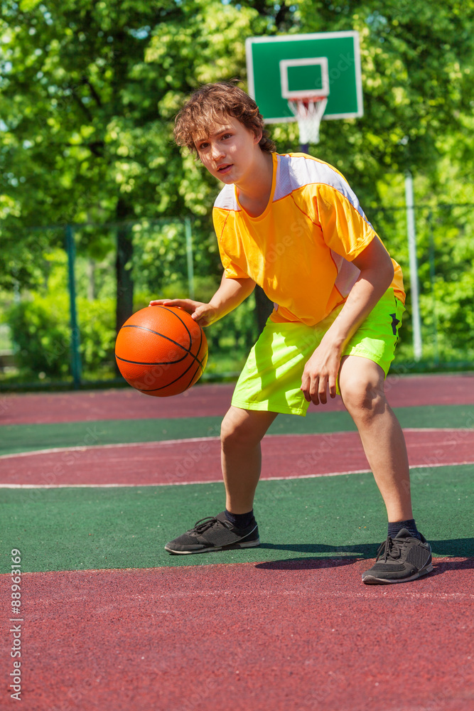 Boy playing with ball alone during basketball game