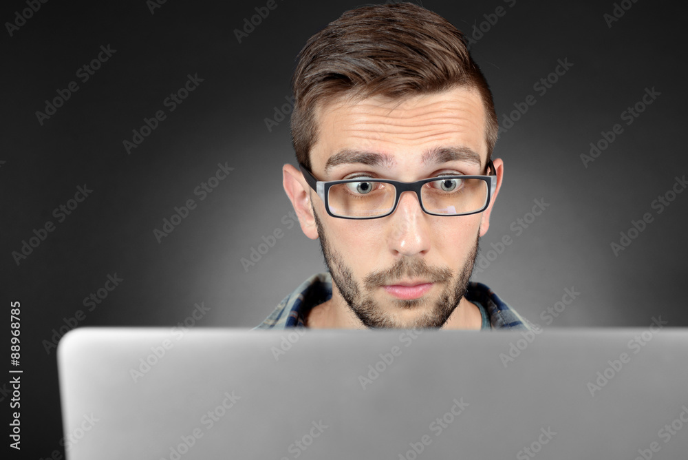 Handsome young man with laptop on grey background Handsome young man with laptop on grey background