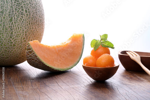 Organic cantaloupe melon in wooden spoon on wooden table