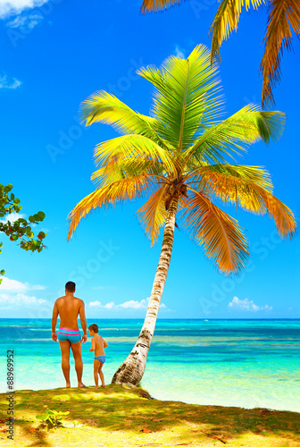 father and son standing on tropical island beach
