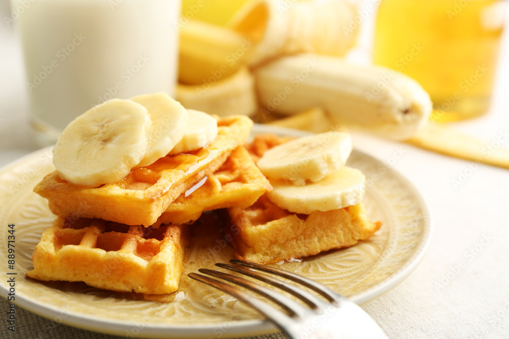 Sweet homemade waffles with sliced banana on plate, on light background Sweet homemade waffles with sliced banana on plate, on light background