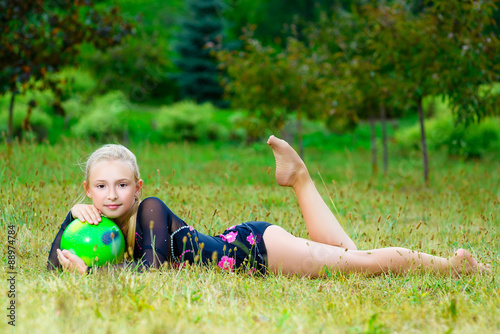 outdoor portrait of young cute little girl gymnast training with