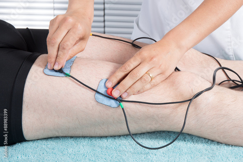 Man getting electric massage for leg muscles in spa