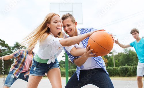 group of happy teenagers playing basketball