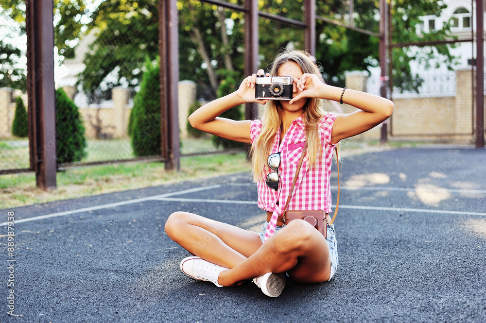 Stylish young woman using a camera to take photo outdoors