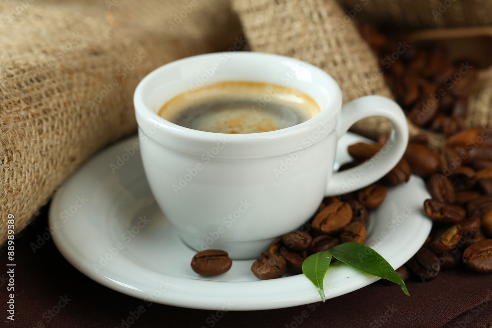 Cup of coffee with beans on table close up