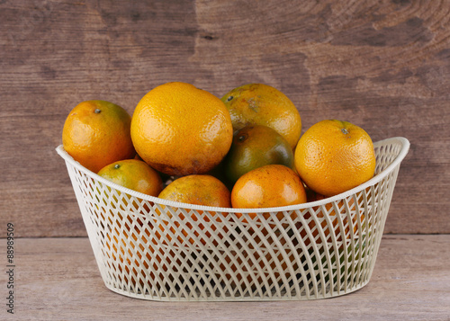 orange fruit in white basket on wood table background