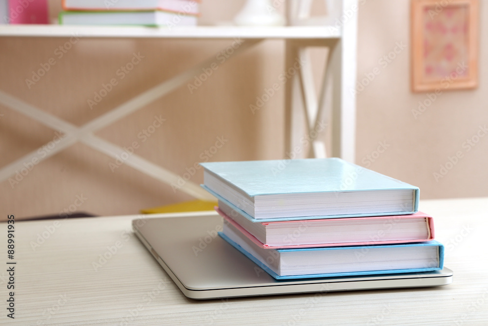 Stack of books with laptop on table in room Stack of books with laptop on table in room