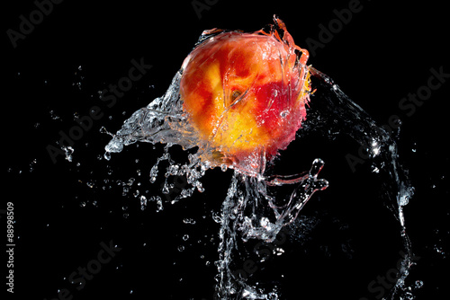 Fresh nectarine in water splash over black background
