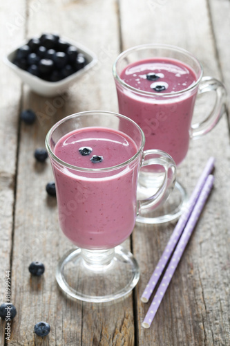 Blueberry smoothie in the glasses on grey wooden background