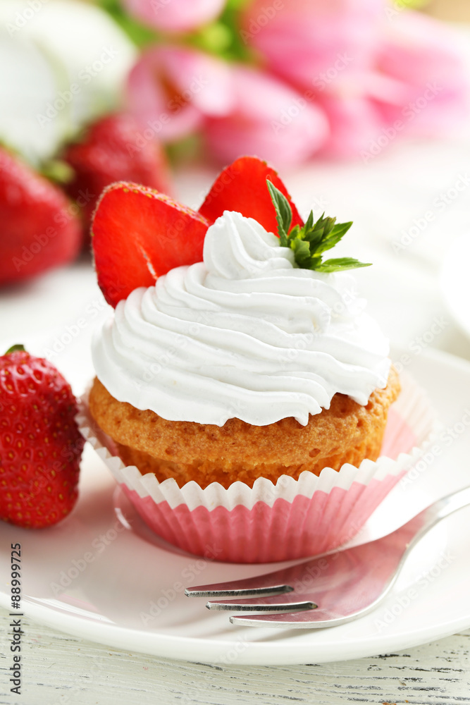 Tasty cupcake with fresh strawberry on white wooden background Tasty cupcake with fresh strawberry on white wooden background