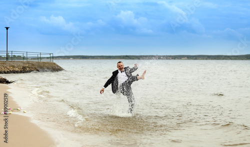 Mężczyzna chlapie wodą na brzegu jeziora.