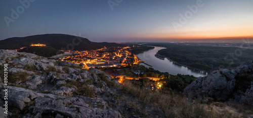 View of Lit Small City with River from the Hill at Sunset