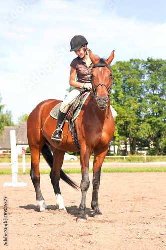 Teenage girl equestrian riding thoroughbred horseback. Vibrant summertime outdoors image. © AnnaElizabeth