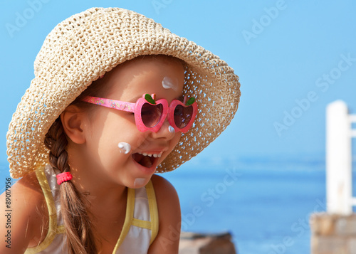 Happy child in glasses with sunscreen on the face