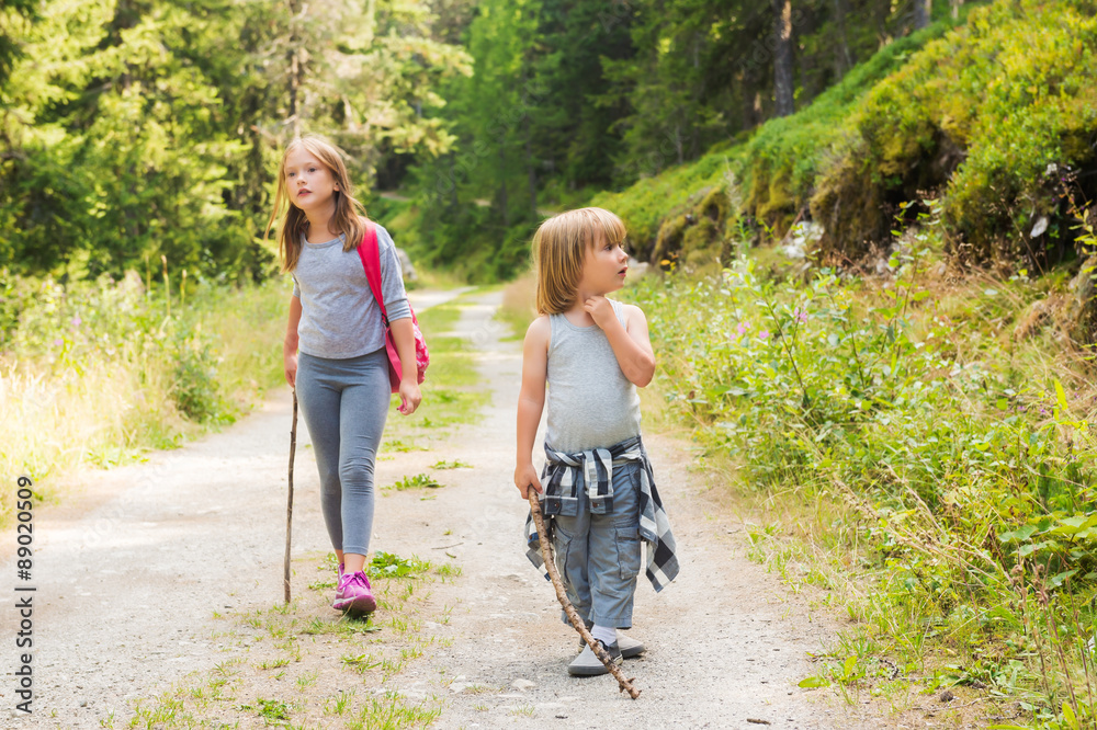 Two cute kids hiking in forest