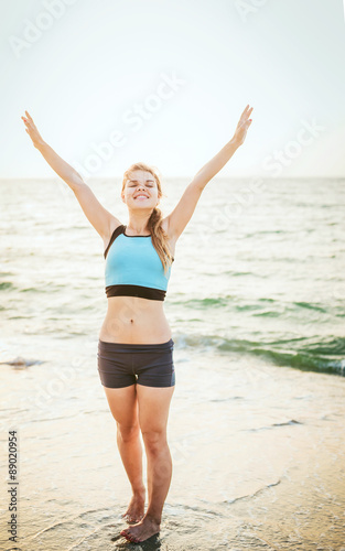  Fitness sport model smiling happy doing exercises during outdoor work out on sunrise. Beautiful caucasian female training outside on seaside in the morning © kurapatka