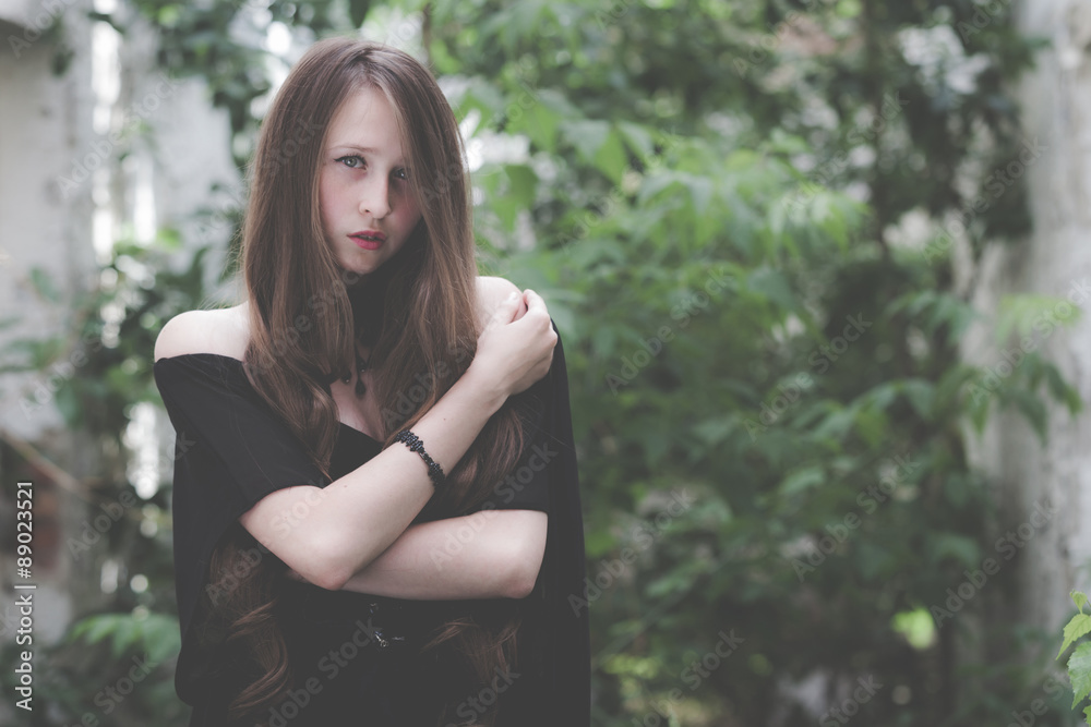 portrait of a beautiful young sad goth girl in an abandoned old