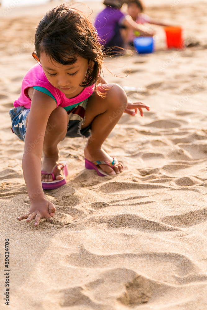 asian little girl writing on the beach sand asian little girl writing on the beach sand