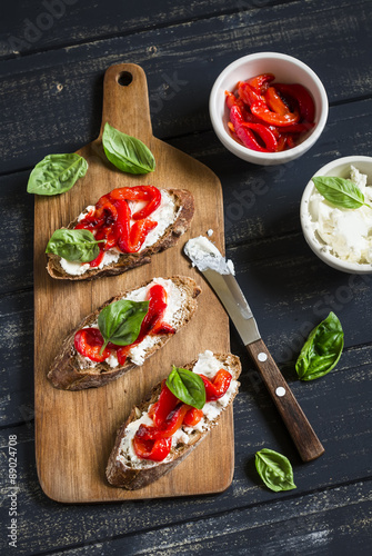 toast with feta cheese, red roasted peppers and Basil on a dark wooden background
