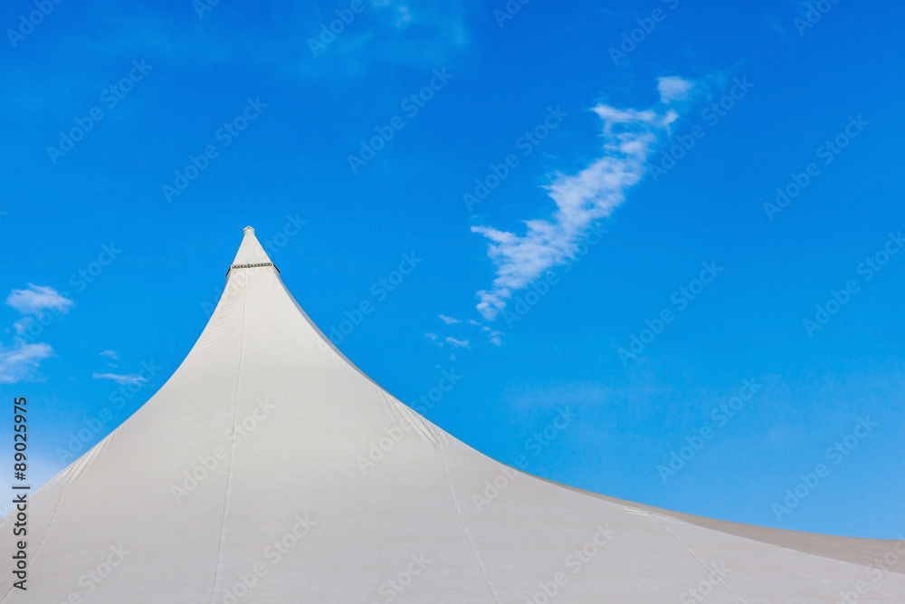 Top of white canvas tent against clear blue sky background.