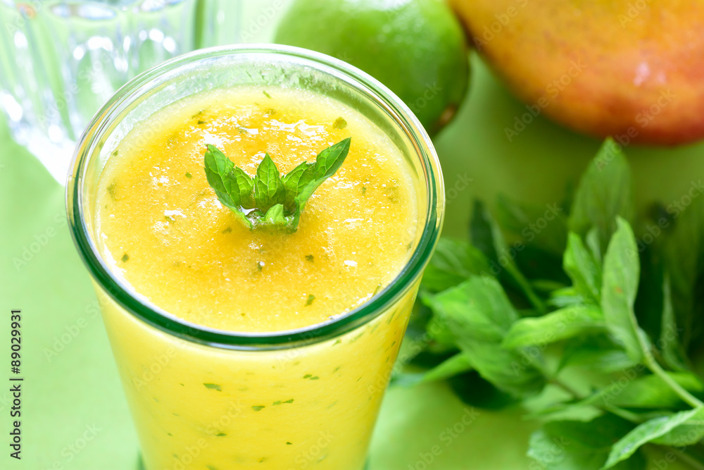 Cooling Mango mint smoothie, summer drink on green table, Yellow Tropical Smoothie made with mango, mint and lime juice. Cooling Mango mint smoothie, summer drink on green table, Yellow Tropical Smoothie made with mango, mint and lime juice.